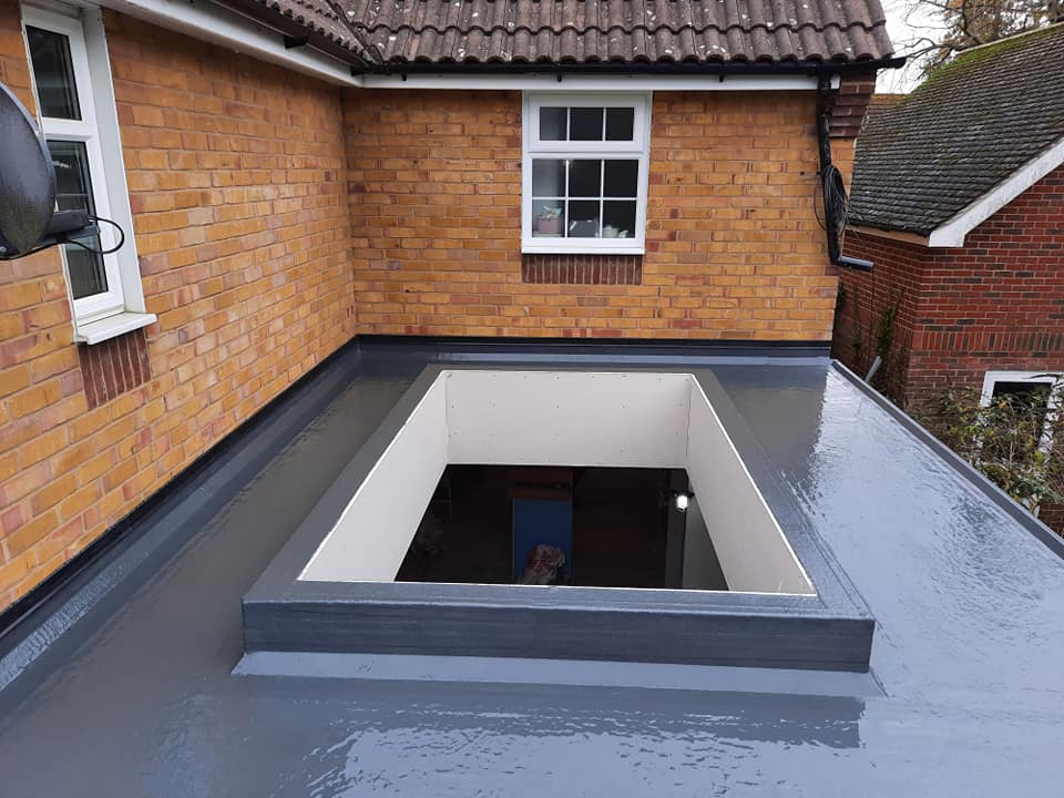 A grey GRP fibreglass flat roof on a brick extension with a square roof lantern opening awaiting a skylight.