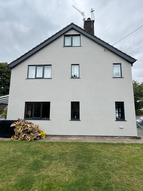 A two-storey detached house finished in fresh light grey exterior wall coating with dark grey window frames and roof tiles.